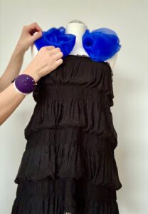 Schwarzes Kleid mit elegantem blauen Rüschen-Detail.